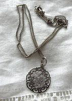 Full view of the sterling silver pendant necklace lying on a white fabric showing chain and pendant details.