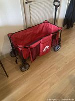 Red Ozark Trail folding wagon fully opened, viewed from side showing interior and side pockets with logo.