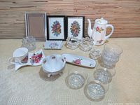 Wide shot of all items in the lot showing assorted ceramic dishware, clear glass bowls, small candle holders, and framed floral prints.