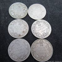 Six Canadian 25 cent silver coins laid flat showing obverse side with maple leaf wreath and dates.