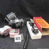 Canon AE-1 camera, damaged Canon case, slide viewer with loose 35mm slide binders and some slides visible, Variant FP electronic flash with box and styrofoam insert