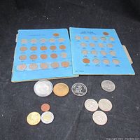 Two blue coin albums with various Canadian coins and a selection of loose coins including world coins and collector pieces.