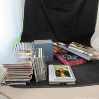 Wide shot showing multiple stacks of CDs and DVDs, some boxes are visible with titles.