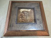 Full view of decorative framed art panel showing textured gold-toned face relief and ornate frame