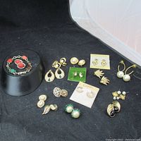 Display of multiple vintage earring sets and bracelet on black surface