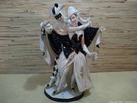 Front view of the ceramic couple figure showing detailed costumes and poses.