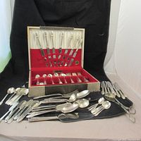 Full view of set with pieces arranged in front of and inside the open black case with red velvet lining