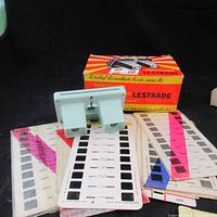 Light blue Lestrade stereoscope viewer alongside original box and several slide strips.
