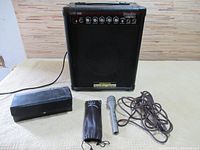 Amplifier and microphone with cable and pouch arranged on floor.