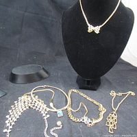 Overview of multiple necklaces displayed on a black velvet necklace bust and laid flat showing different pendant styles and chains.