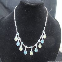 Front view of silver-tone necklace with alternating blue and green teardrop-shaped stones and small blue round stones on chain.