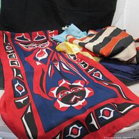 Red, blue, black, and white totem-inspired patterned scarf laid over other scarves showing multiple scarves in the lot.