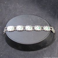 Full view of the sterling silver bracelet laid flat showing the linked panels with dogwood flower enamel designs.