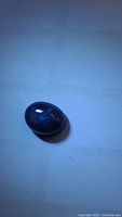 Multiple close-up photos of 2.40 ct blue star sapphire oval cabochon showing deep blue color and surface reflections under light, difficult to capture star flash on camera.