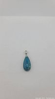 Front view of teardrop-shaped chrysocolla stone pendant with silver bail, showing color and natural pattern.