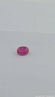 Oval deep pink ruby on white background, top view