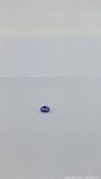 Oval cut tanzanite gemstone placed on a white surface, showing its color and clarity.