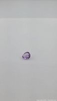 Single loose pear-shaped amethyst gemstone on plain white background showing light pink-purple vibrant color.