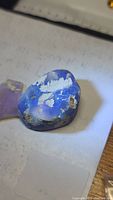 Close-up of large rough Australian opal with blue and purple hues and matrix inclusions.