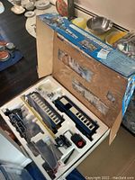 Open box showing the contents of the Blue Comet model train set with locomotive, cars, and track.