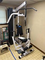 Full assembled view of white and black Body-Solid multi-station gym machine in room corner