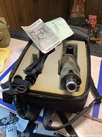 Photo showing the telescope in camouflage design alongside tripod and instruction manual inside the carrying case.