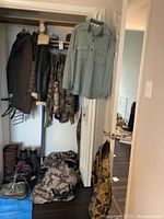 Closet view showing hanging outerwear, boots and duffel bag