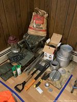 Wide view showing various camping and outdoor items including stools, lantern, charcoal bag, tools, and cookware