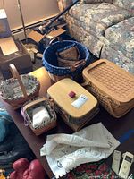 Overall view of the lot showing various woven baskets with fabric liners on a table including a lace textile item.