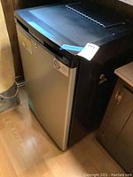 Full front view of the mini fridge with stainless steel door and black sides, showing general condition and size.