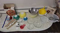 Overview of mixed kitchenware including glass Pyrex bowls, plastic colanders, metal bowl, and boxed Potter & Smith bake set.