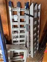 Two aluminum ramps leaning against wooden wall showing full lot.