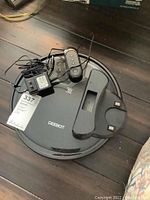 Top view of Deebot DC3G robot vacuum with remote control, power adapter, and charging dock, displaying brand and model identification.