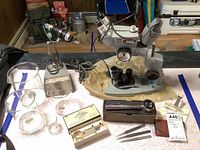 Lot overview showing microscope, lamp, beakers, magnifiers, glass Cornwall piece, and small accessories on table.