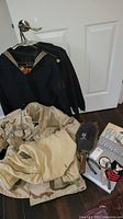 Overall lot of vintage U.S. Navy clothing and accessories including jackets, cap, shovel, spoon, pocket cutter and a history book.