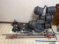 Full view of all weight bars, plates, dumbbells, and rack arranged on floor near wall