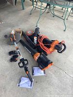 Full view of all items showing trimmer, blower/vac, batteries, cords, manual, battery chargers