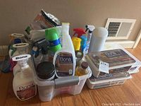 Overview of many Bona cleaning chemical bottles in plastic bins on the floor.