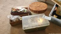 Photo of three boxes: a wooden Shefford cheese box filled with buttons and small items, a green plastic storage box with a clear lid, and an additional cardboard box with more buttons and sewing-related items.