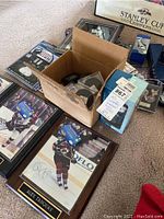 Framed signed photo of Alex Tanguay and collectible memorabilia displayed including pucks, pins, trading cards, and magazines