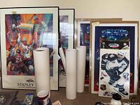 Two framed Colorado Avalanche Stanley Cup posters leaning against the wall, with several rolled posters in front, one Stanley Cup poster clearly visible.