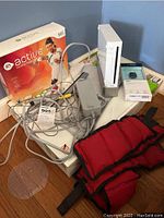 Wii console, EA Sports Active Personal Trainer box, Reddit black weights, power adapter, cables, and FitBit Zip package