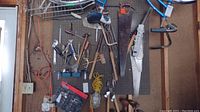 Photo showing a variety of hand tools hanging on a pegboard including saws, hammers, wrenches, screwdrivers, a shop light, snips and clamps.