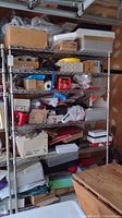 Full front view of the metal shelving unit loaded with various boxes and items showing shelf wire mesh design and pole structure.
