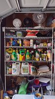 Front view of metal shelving unit filled with various household and garden supplies to illustrate size and condition.