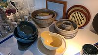 Overview of multiple stoneware and ceramic bowls, plates, and serving dishes in various colors and styles.