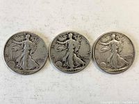 Obverse side of three Walking Liberty silver half dollar coins from 1941, 1945, and 1939, showing Lady Liberty design with varying wear.
