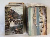 Two stacks of antique postcards showing colorful scenic images including waterfalls and coastal scenes.