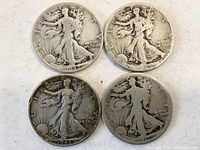 Top obverse view of the four Walking Liberty half dollar coins showing dates 1942 and 1943 with visible wear and detail on Lady Liberty.