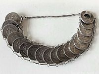 Front view of the bracelet showing 18 linked Mexican 20 Centavos silver coins spaced evenly on a fine metal frame.